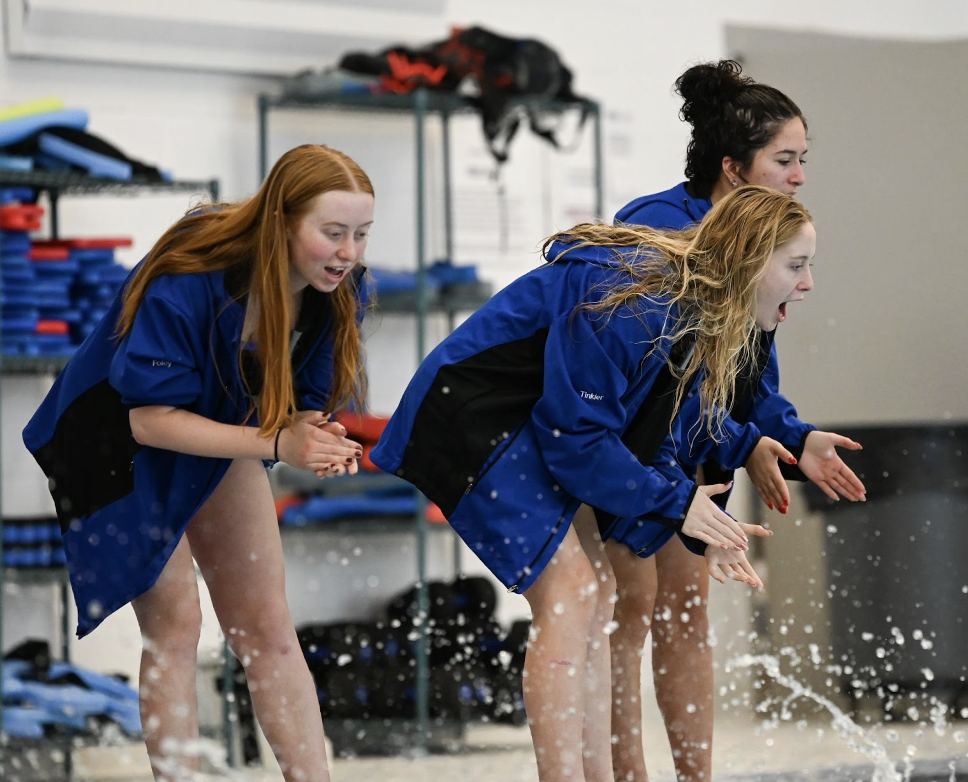 Adelaide Foley (12), Addison Tinkler (11), and Sophia Caballero (11) cheer on their teammates as they race.
